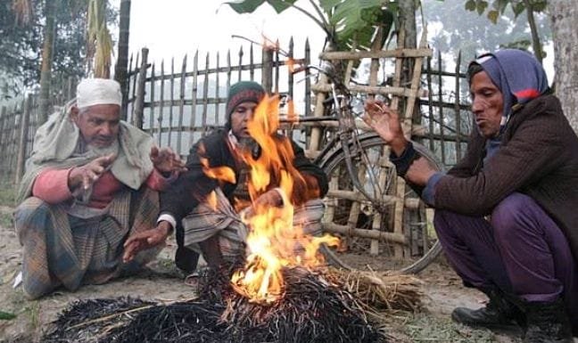শীতের সকালে মানুষ আগুনের তাপে শরীর গরম করছে